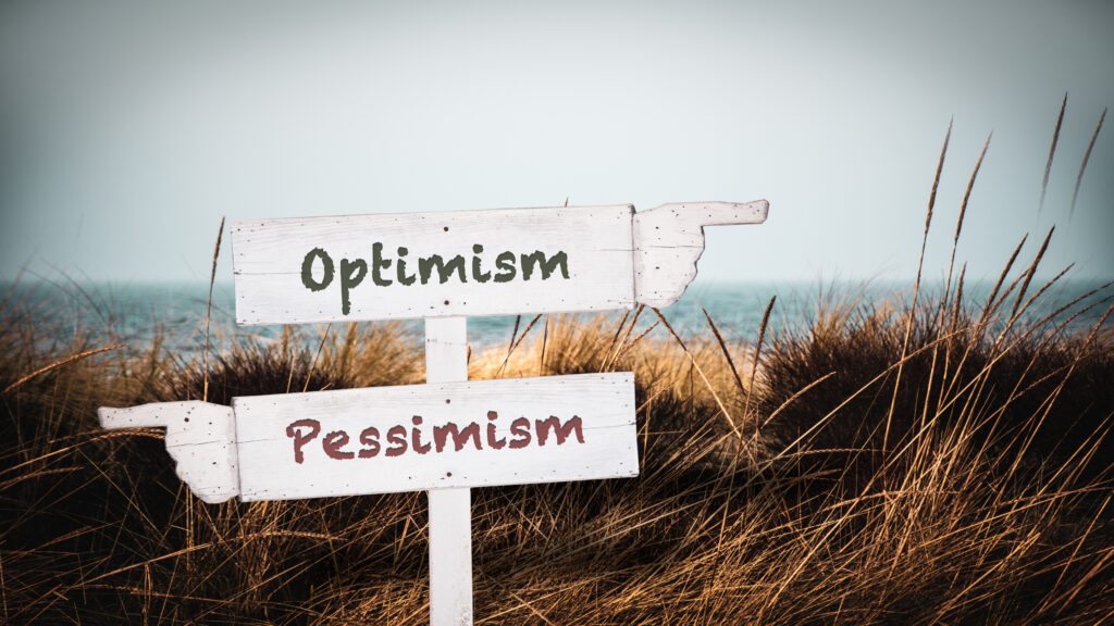 Beach sign with "Pessimism" pointing one way and "Optimism" pointing the other