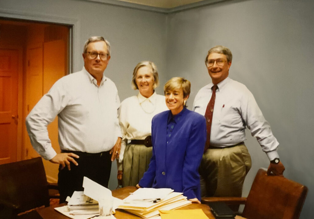 4 people standing around a conference table