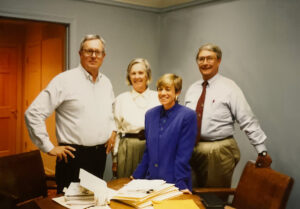 4 people standing around a conference table