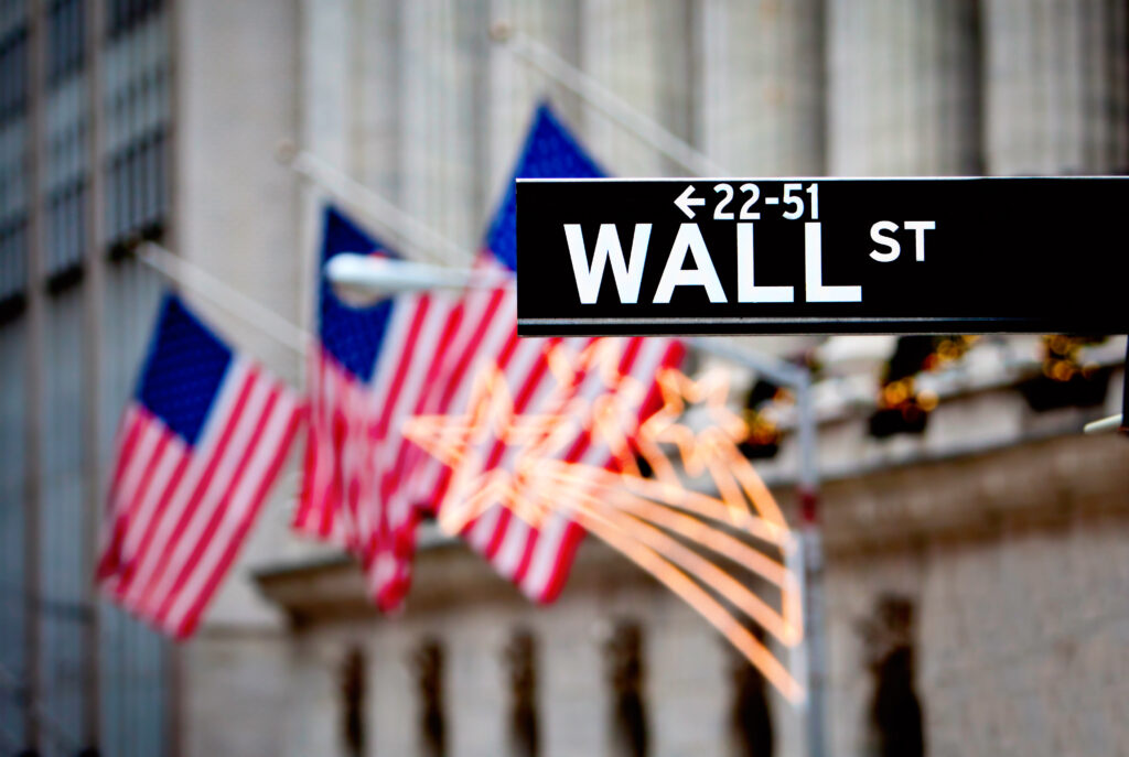 Photo of the Wall Street street sign in front of 3 American Flags in NYC